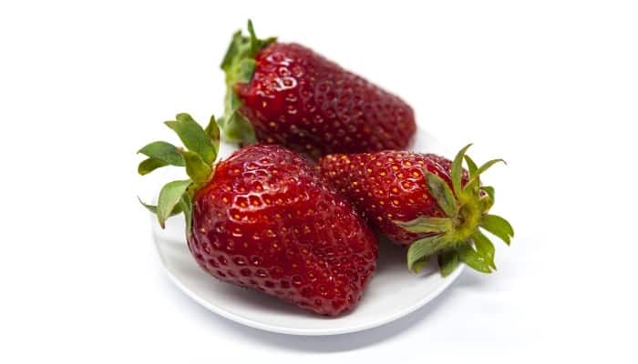 Three Ozark Beauty strawberries resting on a white plate.