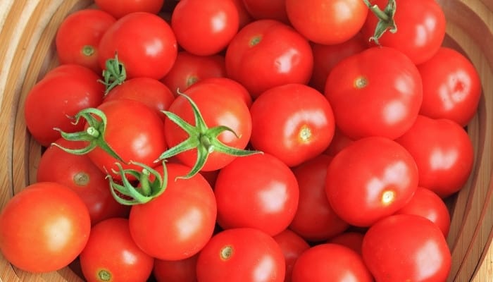 A basket full of red, ripe cherry tomatoes.