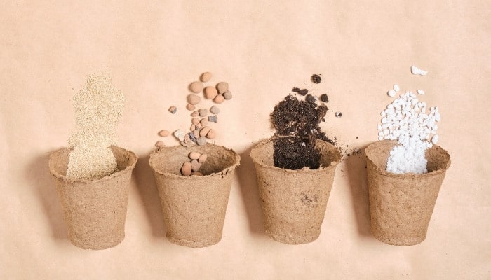 Four peat pots: one with vermiculite, one with clay balls, one with ground bark, and one with perlite set against a peach-colored background.