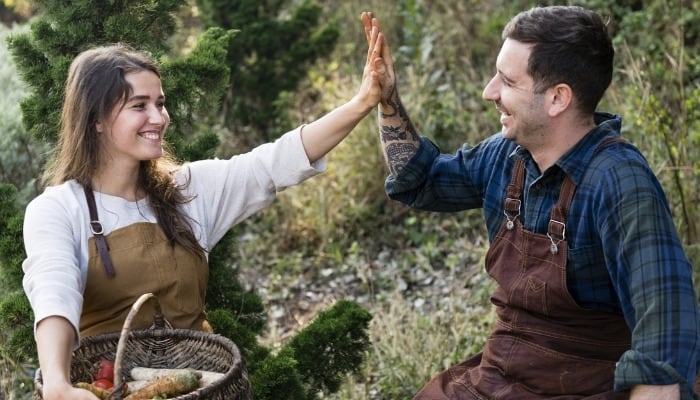 A happy couple celebrates their freshly picked harvest with a high-five.