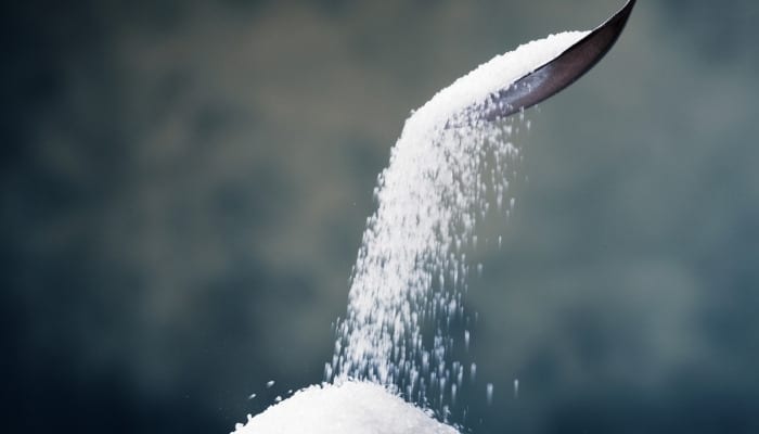 Sugar crystals falling from a spoon held in the air.