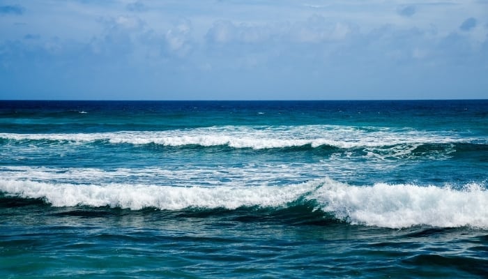 Small waves rolling to shore against a pretty blue sky.