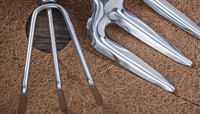 A weed mat made of coco fibers and two garden tools.