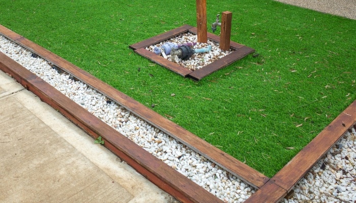Nicely finished landscape timbers separating a concrete path from a manicured lawn.