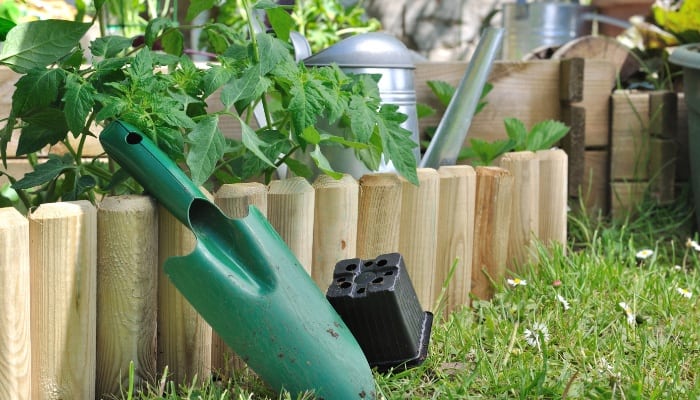 A newly installed pre-formed wood edging border around a small vegetable garden.