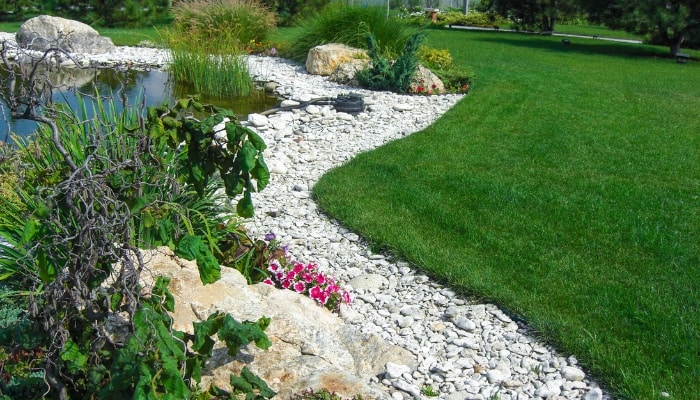 A garden border made of light-colored river rocks.