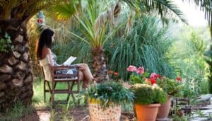 A young woman relaxing in her Florida garden with a book.